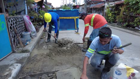 Foremen-wearing-safety-reflective-vests-used-their-shovel,-mixed-cement,-and-demolition-hammer-to-perform-excavation-beside-the-road-gutter-to-install-new-water-piping-from-the-main-water-line