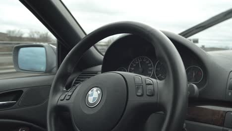 Guy-in-green-rainjacket-is-drives-a-BMW-and-moves-his-and-towards-the-steering-wheel,-Slow-Motion