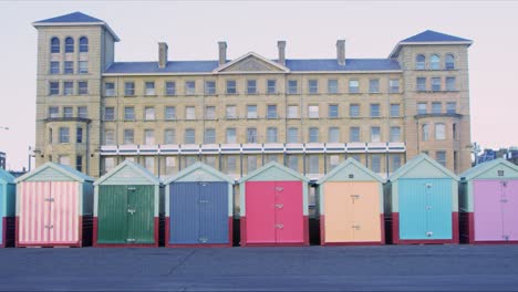 Woman-with-a-dog-walking-past-Brighton-beach-huts