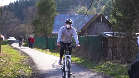 Personas-Que-Usan-Máscaras-Mientras-Andan-En-Bicicleta-En-La-Calle-Cerca-De-Bratislava,-Eslovaquia-Para-Protegerse-Del-Coronavirus---Cámara-Lenta