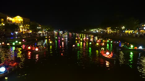 Toma-Panorámica-De-Coloridos-Barcos-En-El-Río-De-Hoi-An-Antigua-Ciudad-Por-La-Noche---Vietnam