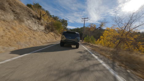 FPV-rotate-and-following-shot-of-Rezvani-driving-on-a-paved-road-in-California