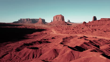 Cierre-De-Toma-Aérea-De-4k-De-Automóviles-Circulando-Por-Una-Carretera-Polvorienta-Que-Serpentea-A-Través-De-Las-Rocas-Rojas-Sangre-Del-Valle-Del-Monumento-En-Arizona