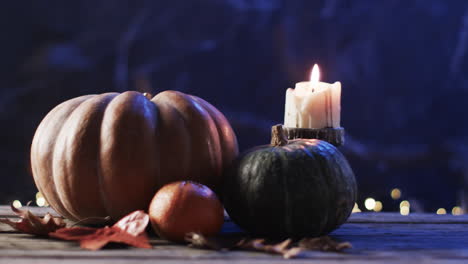 A-candle-burns-beside-pumpkins,-evoking-autumn-vibes