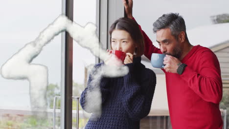 Animation-of-house-shape-over-diverse-couple-drinking-coffee-on-balcony