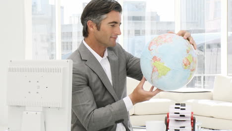 Confident-businessman-looking-at-a-terrestrial-globe