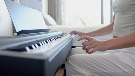 Una-Adolescente-Caucásica-Está-Tocando-Un-Piano-Digital,-Aprendiendo-Una-Pieza