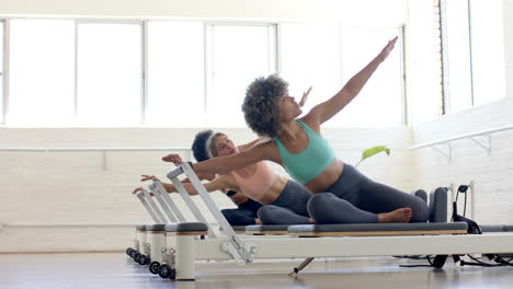 Mujer-Joven-Birracial-Dirigiendo-Pilates,-Otras-Dos-Siguiéndola