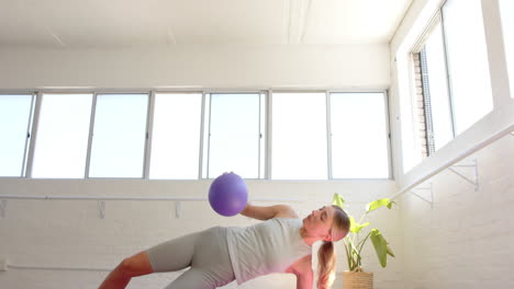 Mujer-Caucásica-Sosteniendo-Una-Bola-Morada-Haciendo-Yoga