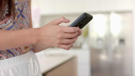 Close-up-of-a-person''s-hands-using-a-smartphone,-with-a-blurred-indoor-background,-with-copy-space