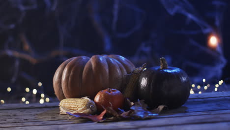 Pumpkins-and-corn-rest-on-a-wooden-surface-at-night,-with-copy-space