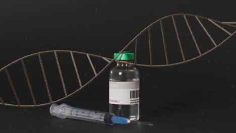Animation-of-dna-strand-over-syringe-and-vaccine-vial-on-black-background