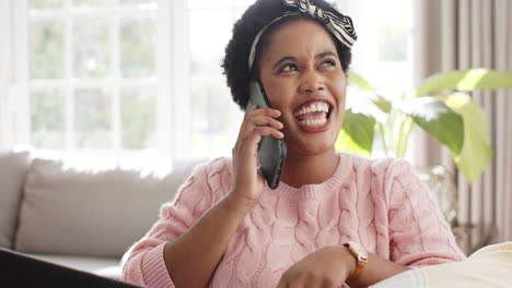 Una-Mujer-Afroamericana-Charla-Por-Teléfono-En-Casa,-Su-Sonrisa-Radiante