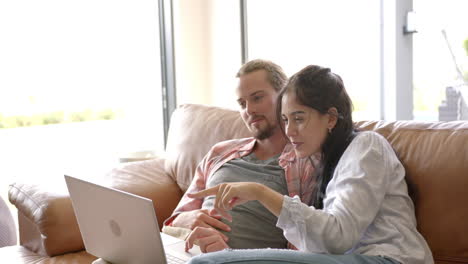 A-biracial-couple-is-using-a-laptop-at-home-on-the-couch
