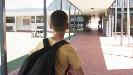 Biracial-boy-with-a-backpack-stands-in-a-school-corridor