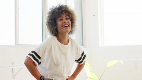 A-biracial-young-woman-with-curly-brown-hair-is-smiling,-hands-on-hips