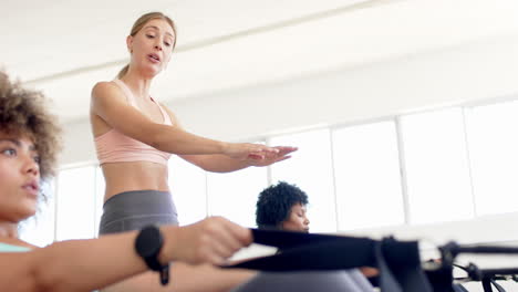 Mujer-Caucásica-Liderando-Clase-De-Pilates,-Mujeres-Birraciales-Siguiendo