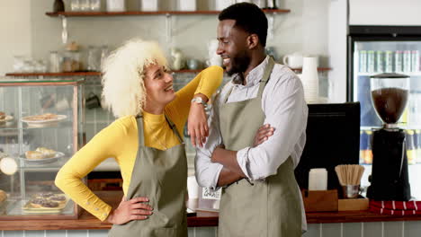 Barista-team-of-biracial-woman-and-African-American-man-stand-together-with-confident-smiles