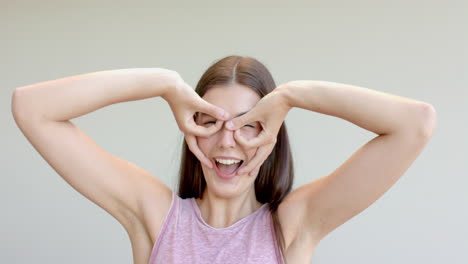 Teenage-Caucasian-girl-makes-a-playful-gesture-with-her-hands-at-home