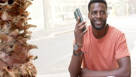 Ein-Junger-Afroamerikanischer-Mann-Lächelt,-Während-Er-Im-Freien-Telefoniert