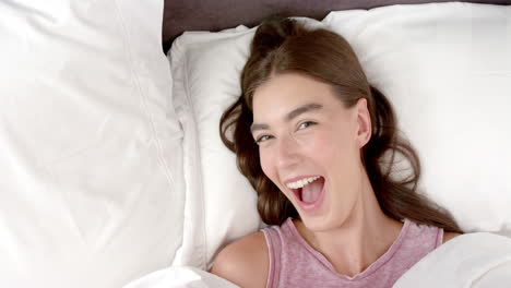 A-teenage-Caucasian-girl-with-brown-hair-is-laughing-while-lying-in-bed-at-home