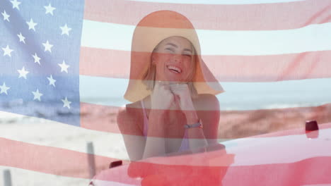 Animation-of-flag-of-usa-over-caucasian-woman-by-car-on-beach