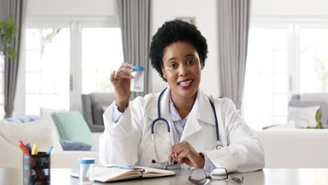 African-American-female-doctor-in-a-white-lab-coat-examines-a-test-tube-on-video-call-consultation