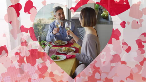 Animation-of-hearts-over-diverse-couple-eating-dinner-and-drinking-wine-at-home