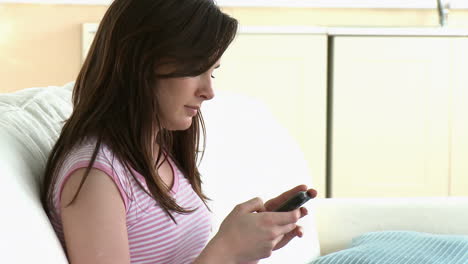 Concentrated-woman-sending-a-text-sitting-on-a-sofa