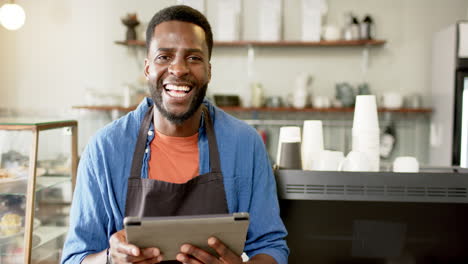 Ein-Fröhlicher-Afroamerikanischer-Barista-Hält-Ein-Tablet-In-Einem-Hellen-Café-Ambiente