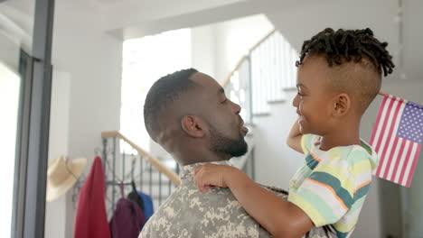 Afroamerikanischer-Vater-In-Militäruniform-Hebt-Seinen-Sohn-In-Einer-Häuslichen-Umgebung-Zu-Hause-Hoch