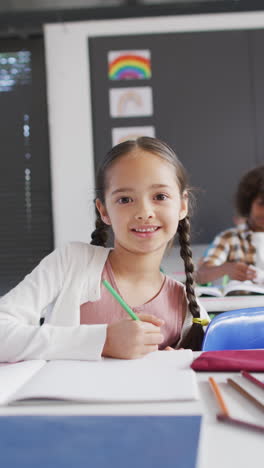 Vertical-video-of-portrait-of-happy-biracial-schoolgirl-in-school