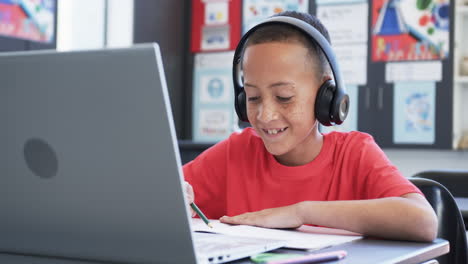 Biracial-boy-with-freckles-focuses-on-schoolwork-at-laptop,-copy-space