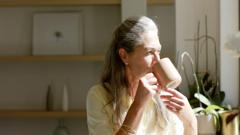 A-mature-Caucasian-woman-holding-mug,-looking-away-thoughtfully