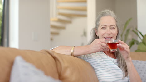 Caucasian-mature-woman-holding-tea,-sitting-on-couch