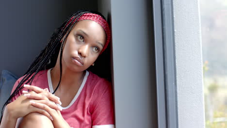A-young-African-American-female-sitting-by-window,-looking-outside