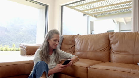 Mujer-Madura-Caucásica-Sentada-En-El-Sofá,-Mirando-El-Teléfono-Inteligente