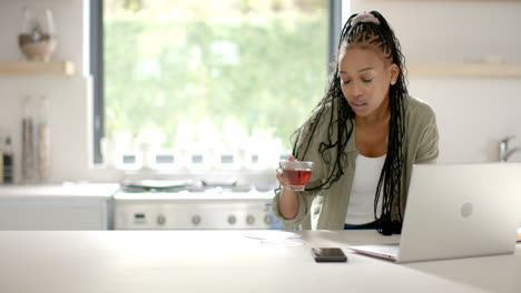 Mujer-Joven-Afroamericana-Bebiendo-Té-Y-Usando-Una-Computadora-Portátil