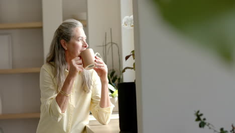 Mature-Caucasian-woman-holding-coffee,-looking-outside