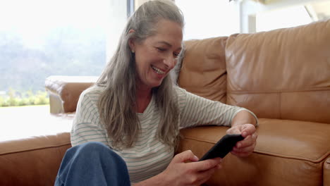 Caucasian-woman-sitting-on-couch,-looking-at-phone