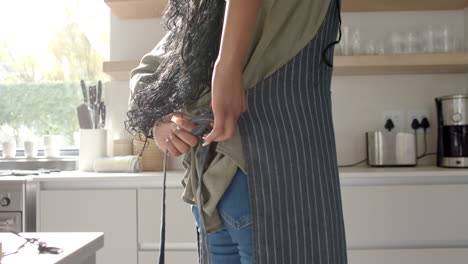 African-American-young-woman-holding-smartphone-in-kitchen