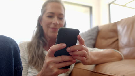 Caucasian-mature-woman-holding-smartphone,-laughing