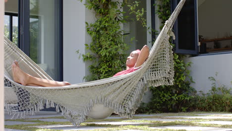 African-American-young-professional-relaxing-in-hammock-outside-a-modern-home