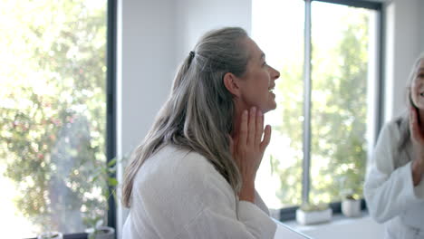 A-mature-Caucasian-woman-checking-her-face-in-mirror