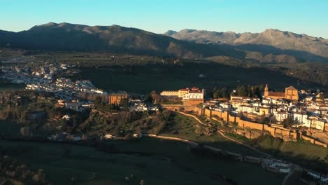 Aerial-Drone-Of-Ronda-Surrounded-City-Wall-From-El-Andaluz-Moorish-Islamic-era-in-Spain-During-Golden-Hour-Sunset