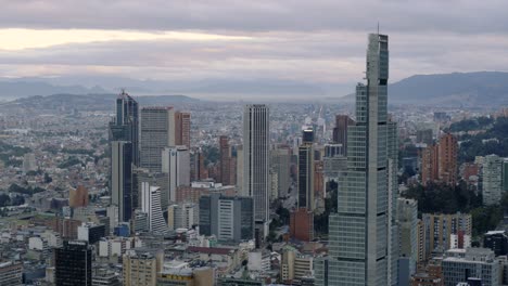 Drone-shot-of-downtown-Bogota,-Colombia-at-sunrise-on-a-cloudy-day