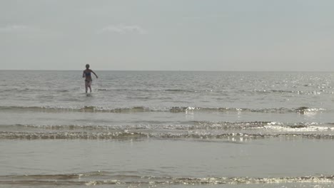 Hermosa-Cámara-Lenta,-Salpicaduras,-Chica-Corriendo-Hacia-La-Costa-De-La-Playa