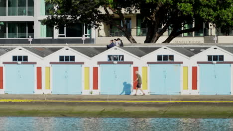 A-man-walks-past-Wellington-boat-sheds-in-New-Zealand