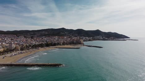 Sitges-coast-and-cityscape-with-mountains-in-the-background,-aerial-view