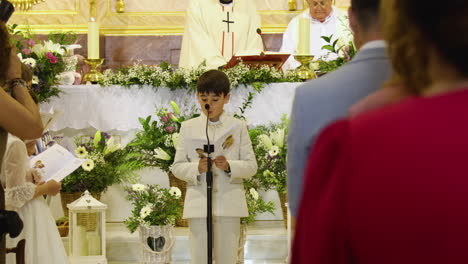 Niño-Español-Habla-Por-Un-Micrófono-Durante-El-Servicio-De-Primera-Comunión-En-Una-Iglesia